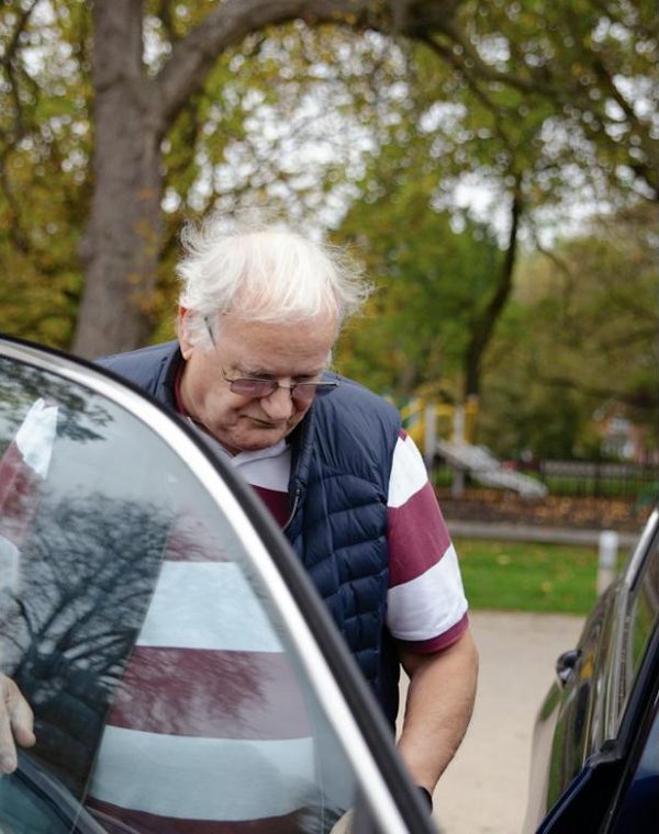 An older man getting into a car