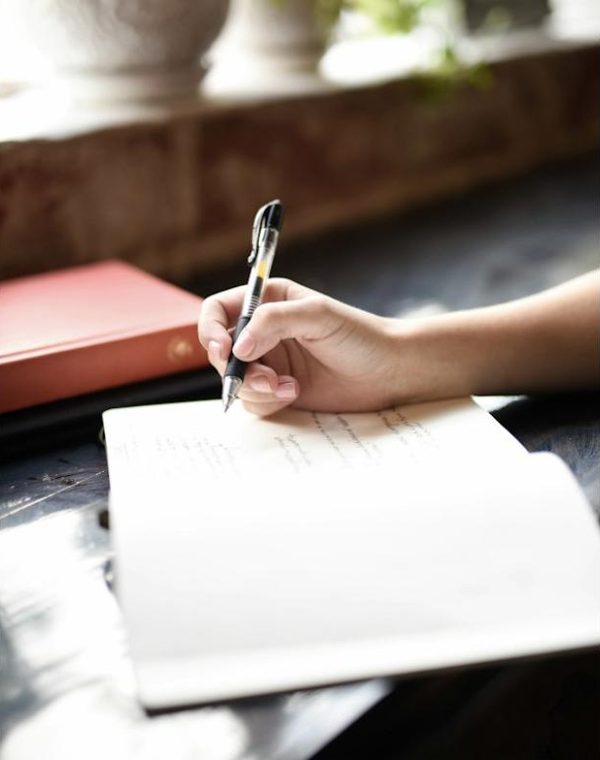 A hand filling out a form with a pen